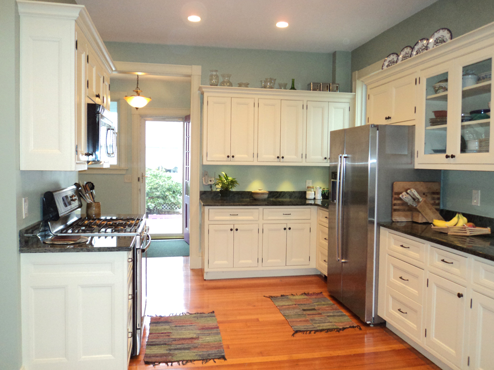 View of a kitchen in Newton. Blue walls, white cabiets and black counters