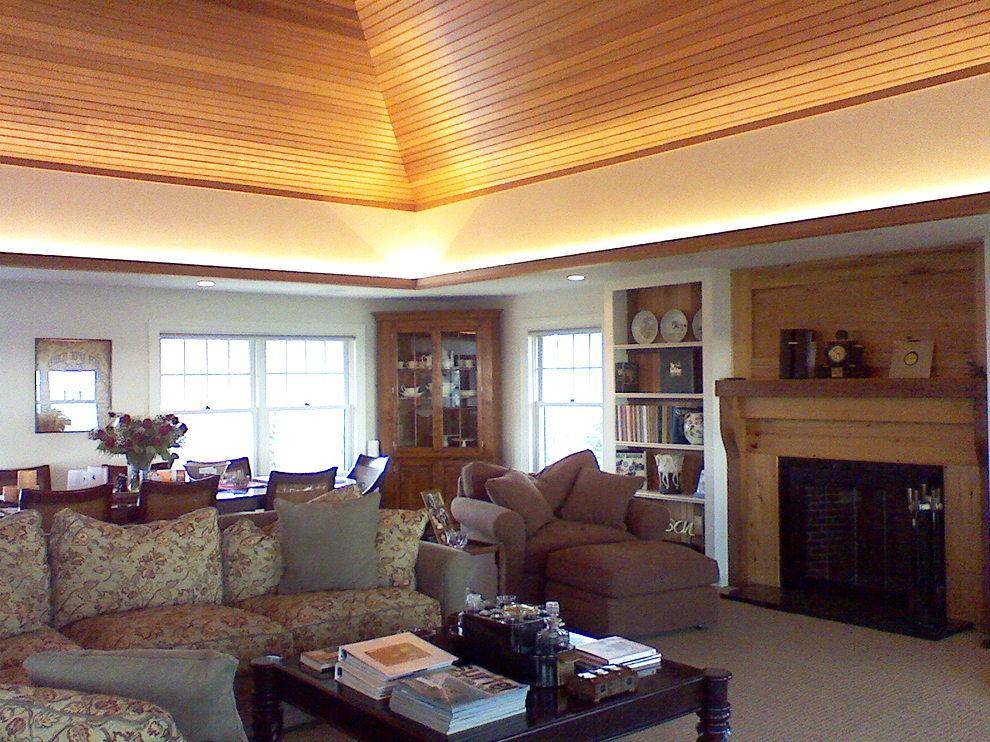 AFTER - Adding various woods to the fireplace facade and ceiling gives the start of warmth throughout the space. Adding cove lighting, warm shades in the upholstery fabric and rich woods to the hard goods completes the room and draws you into it.